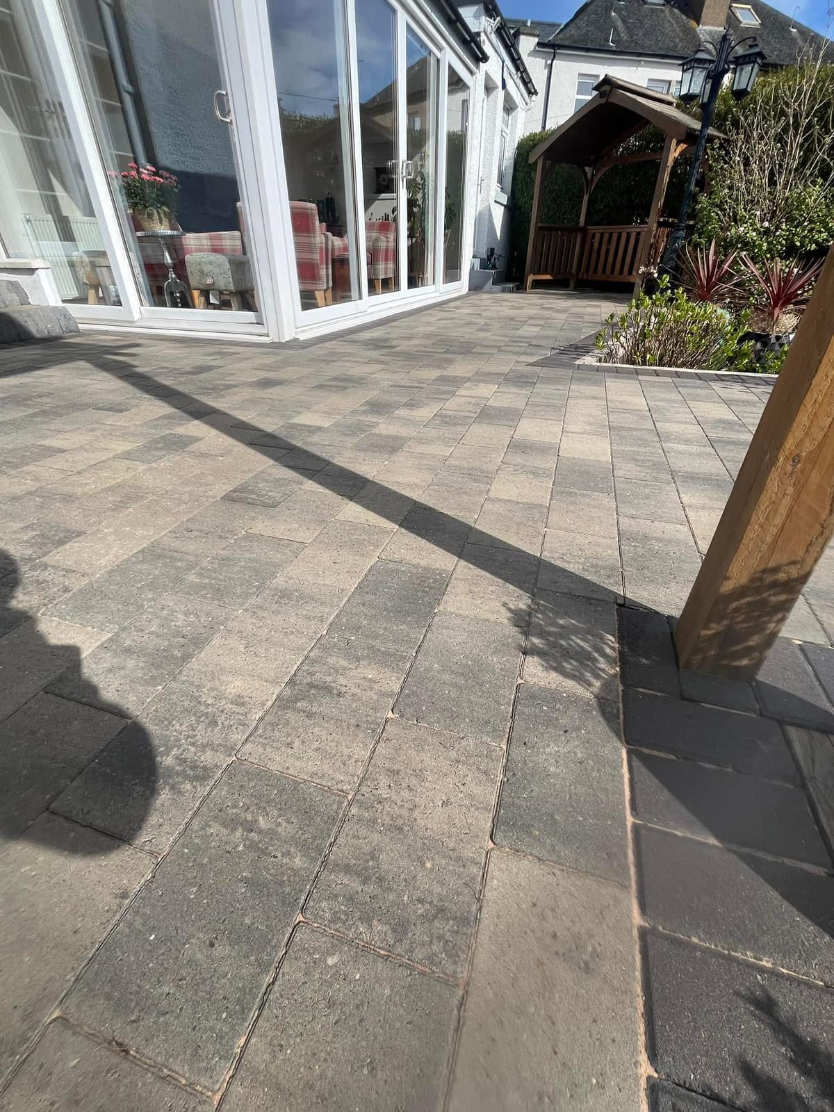 Cleaned block paving running from a conservatory across to a garden shelter