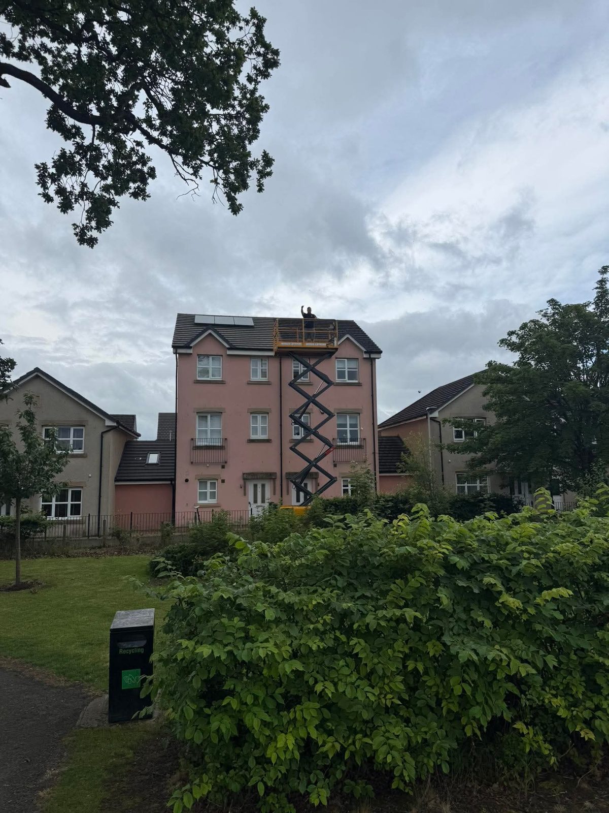 Scissor lift raised to roof level on a four-storey block for high-level access
