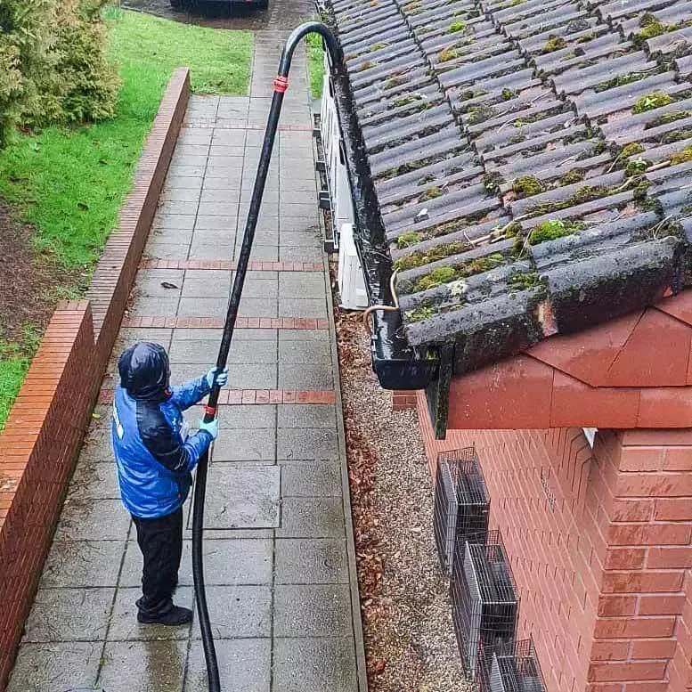 Operative clearing moss and debris from a gutter with a gutter vacuum pole