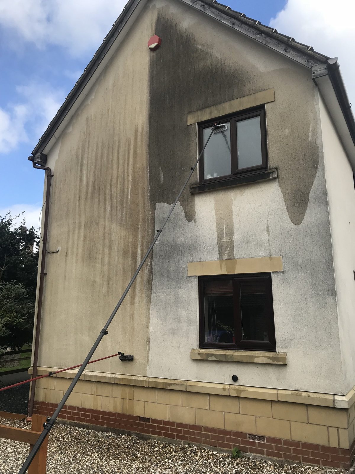 Rendered gable part way through a clean, the cleaned section beside the algae-stained original